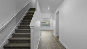 Staircase featuring wood finished floors and recessed lighting
