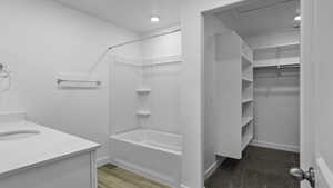Bathroom with shower / bath combination, vanity, and a walk in closet
