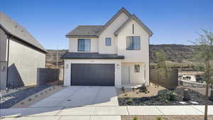View of front of property with stucco siding, an attached garage, and driveway