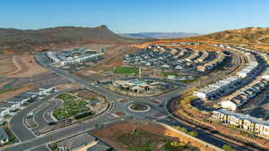 Aerial view of property and surrounding area featuring a mountainous background and nearby suburban area