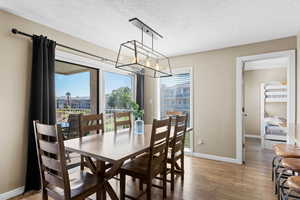 Dining room with healthy amount of natural light, hardwood / wood-style flooring, a textured ceiling, and a chandelier