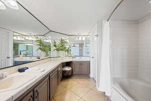 Bathroom featuring a textured ceiling, light tile patterned floors, vanity, and shower / tub combo with curtain
