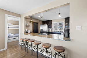 Kitchen featuring a breakfast bar, hanging light fixtures, light stone countertops, and a textured ceiling