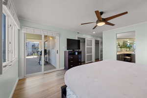 Bedroom featuring wood finished floors, access to outside, a ceiling fan, a textured ceiling, and ornamental molding
