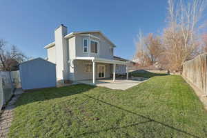 Rear view of house with a storage shed, a fenced backyard, a patio area, and a chimney