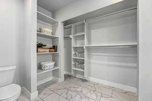 Spacious walk-in ensuite closet featuring light marble finish floors