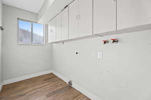 Washroom featuring hookup for a washing machine, cabinet space, dark wood-type flooring, and electric dryer hookup