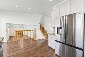 Kitchen with stainless steel fridge, white cabinetry, dark wood-style flooring, recessed lighting, and dark stone counters