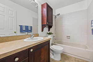 Full bathroom with vanity,  shower combination, light tile patterned flooring, and a textured ceiling