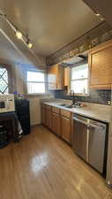 Kitchen featuring dishwasher, white microwave, brown cabinetry, and healthy amount of natural light