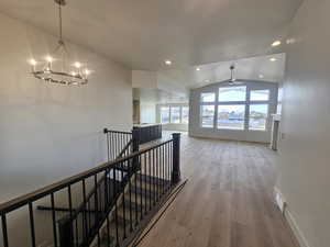 Corridor featuring light wood-style floors, an upstairs landing, and hanging lights