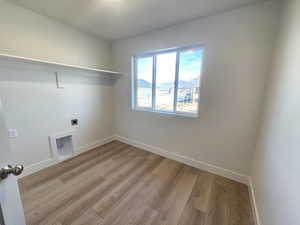 Laundry area with light wood finished floors and electric dryer hookup