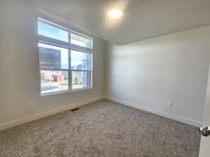 Carpeted spare room featuring baseboards