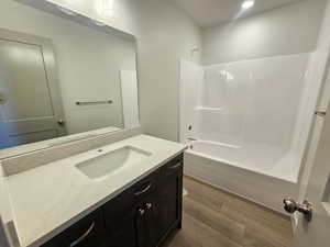 Bathroom featuring vanity, bathtub / shower combination, dark wood finished floors, and recessed lighting