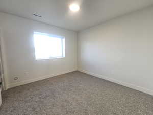 Carpeted spare room featuring baseboards