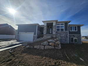 Prairie-style home with stone siding, driveway, and a garage