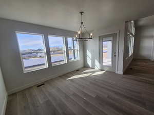 Unfurnished dining area featuring a chandelier, wood finished floors, and a water view