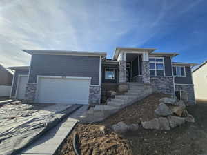 Prairie-style home with stone siding, driveway, and a garage