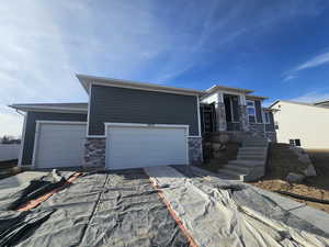 Prairie-style house featuring stone siding, driveway, and an attached garage