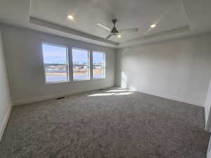 Carpeted spare room with a ceiling fan, a raised ceiling, and recessed lighting