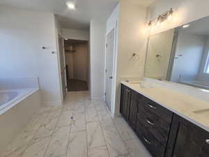 Bathroom with a garden tub, light marble finish floors, a spacious closet, and double vanity