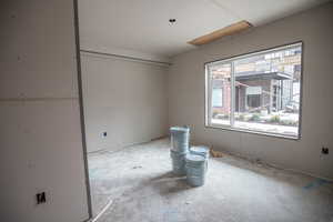 Unfurnished room featuring unfinished concrete floors and attic access