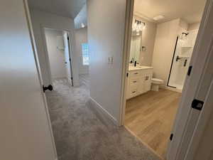 Full bath featuring light carpet, vanity, a textured ceiling, a stall shower, and light wood-type flooring