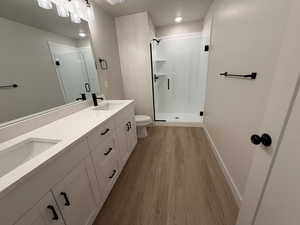 Full bath featuring double vanity, a shower stall, light wood-type flooring, and recessed lighting