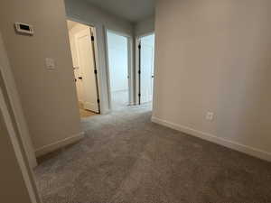 Corridor with light colored carpet and baseboards