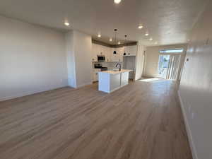 Kitchen with open floor plan, white cabinetry, pendant lighting, light countertops, and recessed lighting