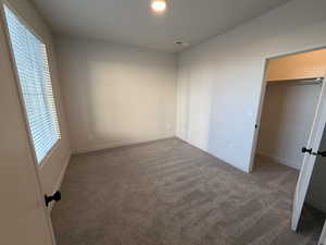 Unfurnished bedroom featuring dark colored carpet and a spacious closet
