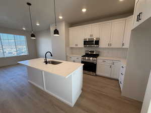 Kitchen with appliances with stainless steel finishes, white cabinets, pendant lighting, a center island with sink, and recessed lighting
