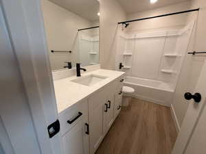 Full bathroom featuring vanity, bathing tub / shower combination, and dark wood-style flooring