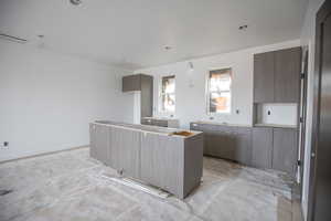 Kitchen featuring modern cabinets, a kitchen island, concrete floors, and dark brown cabinets