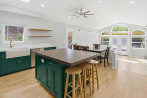 Kitchen with green cabinetry, light wood finished floors, open shelves, stainless steel dishwasher, and recessed lighting