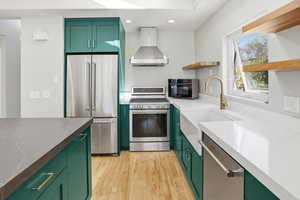 Kitchen with green cabinets, stainless steel appliances, open shelves, recessed lighting, and light wood-style floors
