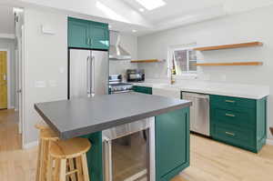 Kitchen with green cabinetry, beverage cooler, and a kitchen bar