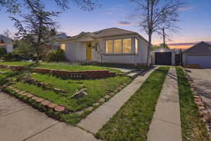 Bungalow featuring an outbuilding, a detached garage, brick siding, and a shingled roof