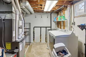 Washroom featuring concrete floors, independent washer and dryer, and heating unit