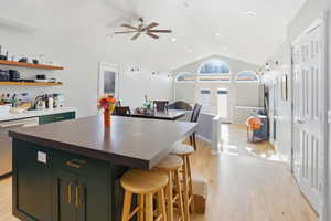 Kitchen featuring vaulted ceiling, a breakfast bar, open floor plan, a center island, and french doors
