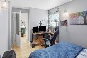 Bedroom with light wood-style flooring and an office area