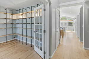 Hall with vaulted ceiling, light wood-type flooring, and recessed lighting