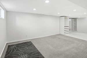 Finished basement with light colored carpet and recessed lighting