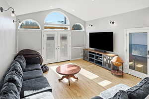 Living area featuring french doors, light wood-style floors, and lofted ceiling