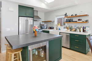 Kitchen featuring green cabinetry, beverage cooler, open shelves, a kitchen bar, and recessed lighting