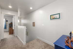 Hall with an upstairs landing, carpet floors, and recessed lighting