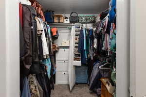 Spacious closet with dark colored carpet off the primary bedroom and bathroom