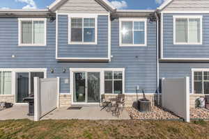 Rear view of house featuring a patio area and stone siding