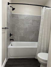 Full bathroom featuring shower / bath combo with shower curtain and dark wood-style flooring