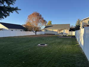 Fenced backyard with a patio and a fire pit